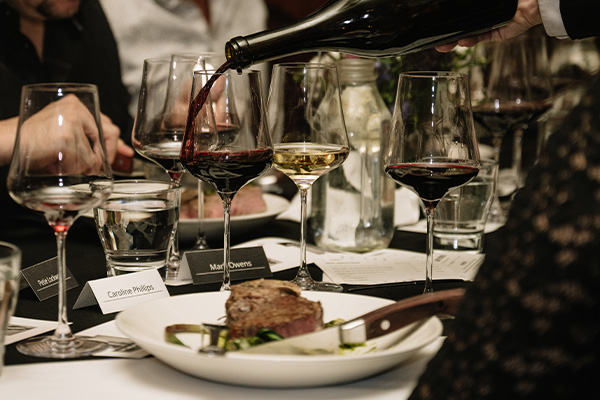 Pouring wine into glass with steak off to the side